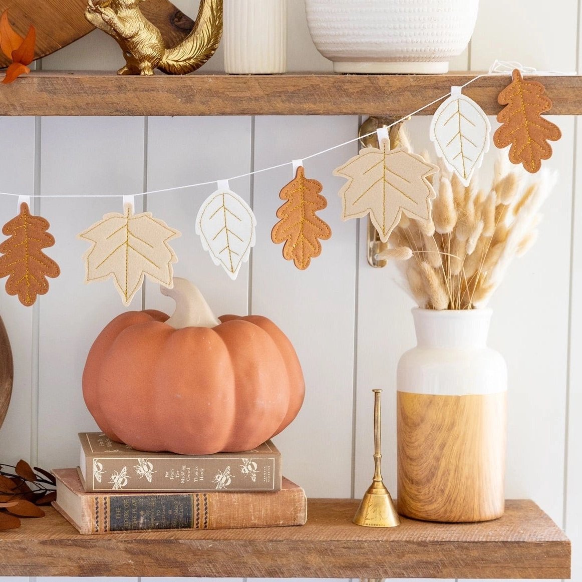 A cozy shelf decorated for fall, featuring a charming Thanksgiving garland made of felt leaves in warm autumn tones. Perfect for adding a festive touch to any Thanksgiving setup.