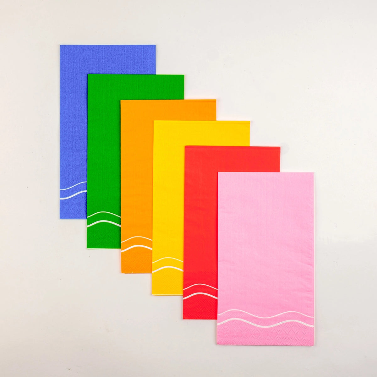 Set of colorful paper guest towels featuring green, blue, yellow, orange, red, and pink napkins, each with white wavy lines, perfect for rainbow party supplies and decorative paper napkins.