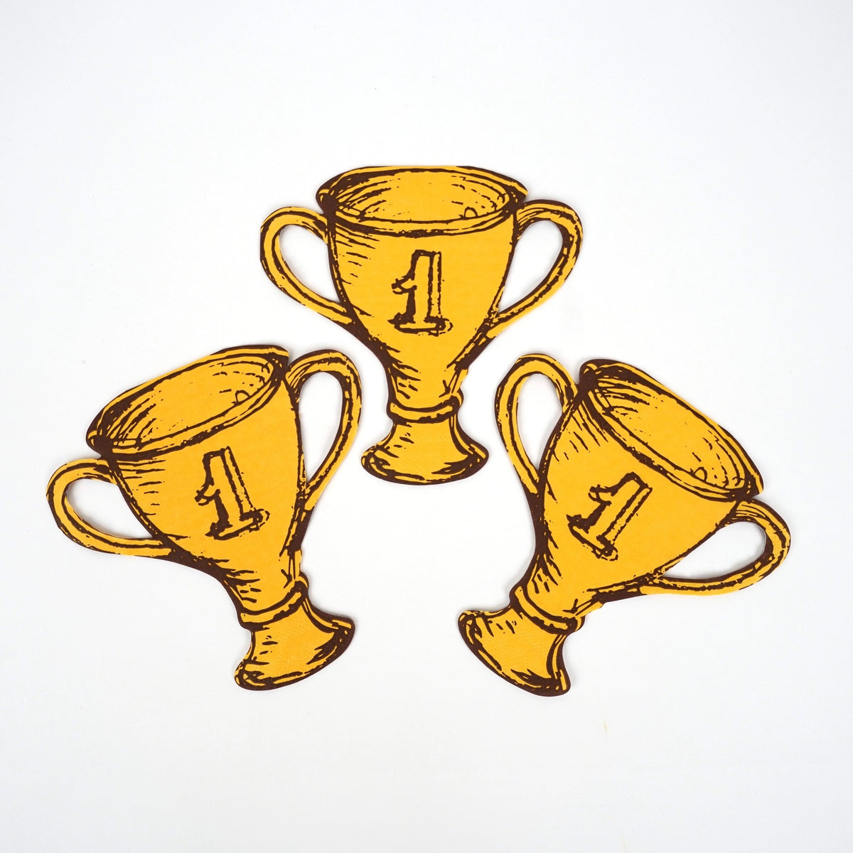 Three golden trophy-shaped paper napkins arranged on a white background, perfect for adding a winning touch to any sports themed birthday party.