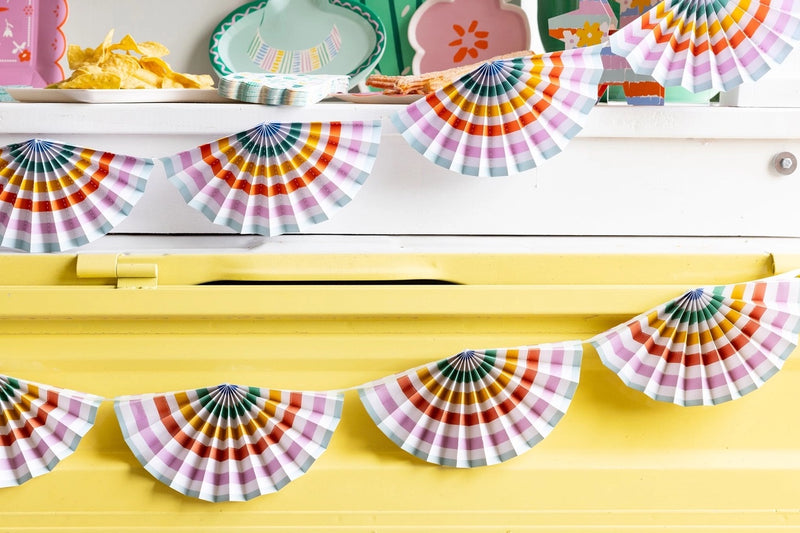 Brightly colored Fiesta Striped Fan Banner displayed as party decor with margaritas and festive tableware.