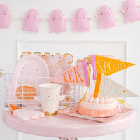 Halloween party display with pink ghost cups, pink ghost garland, and other themed decorations, ideal for creating fun pink Halloween decor.