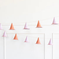 6-foot Halloween garland with 12 pink and gold witch hats, featuring glittery brims and gold foil stars, hung against a white wall.