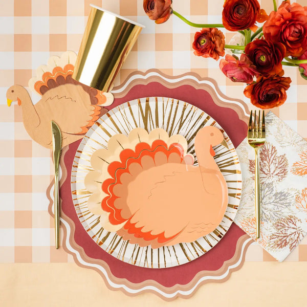 Maroon paper placemat with scalloped edges on a Thanksgiving table setting.