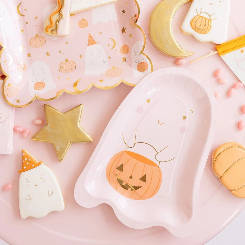 A close-up of Halloween party supplies featuring a ghost-shaped plate, a pink ghost cup, and a mini pennant.