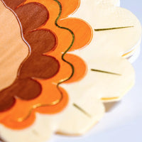 A close-up of the scalloped edge of turkey napkins showcasing the rich brown, orange, and gold accents. These Thanksgiving paper napkins bring festive detail to any holiday table setting.