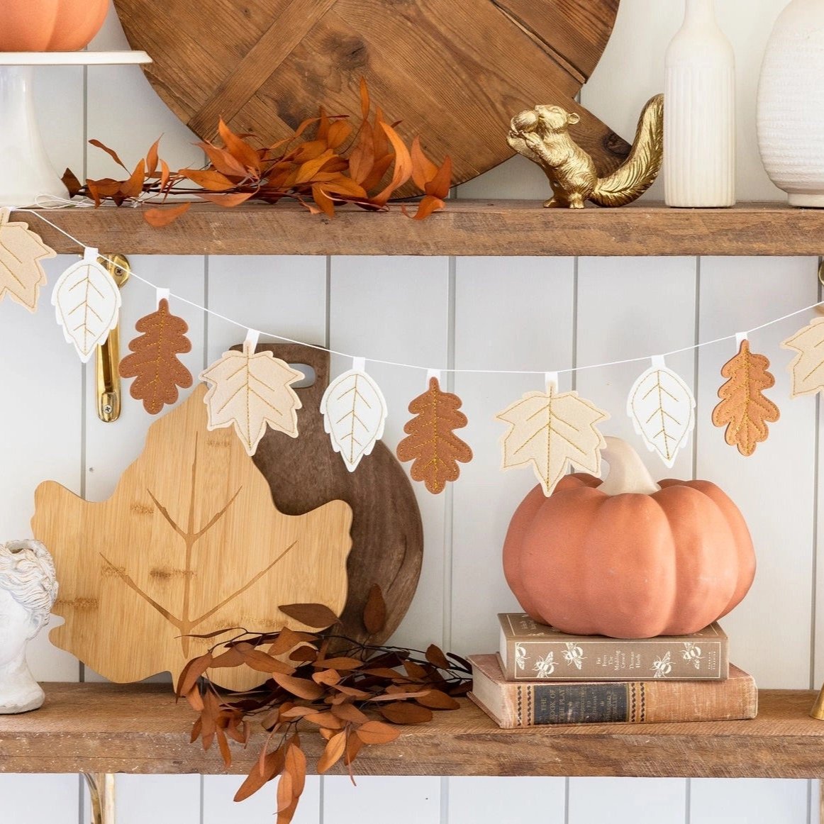 A beautifully styled shelf featuring a Thanksgiving garland with felt leaves. The garland adds a warm and inviting touch to the autumn decor, paired with pumpkins and wooden accents.