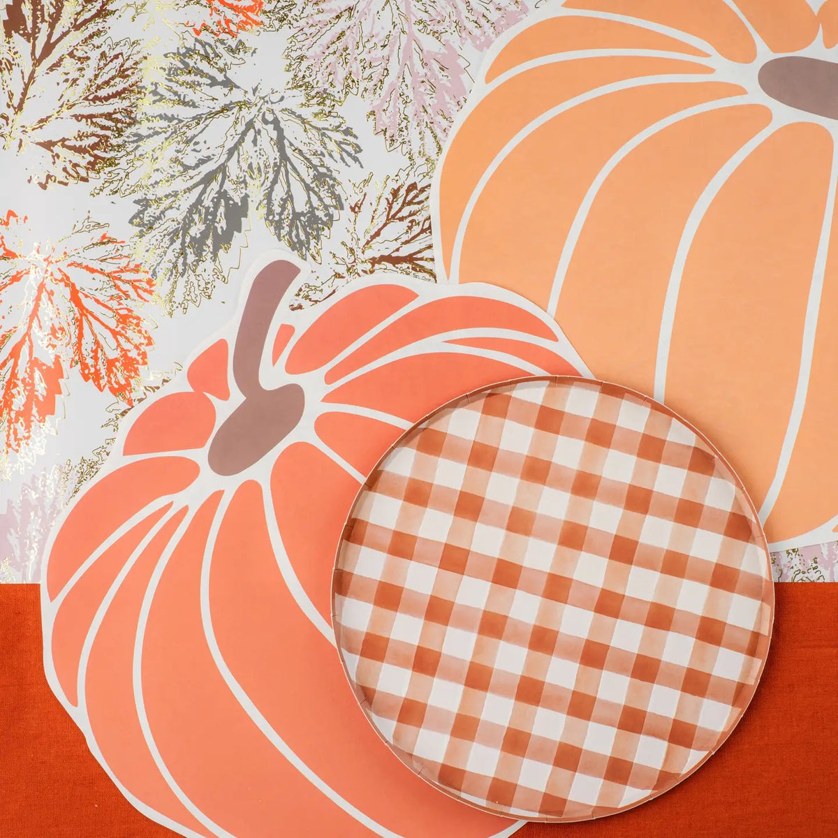 Brown and white watercolor gingham paper plate with pumpkin charger plates and a fall leaf table runner.