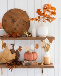 A Thanksgiving garland with felt leaves hangs across a rustic shelf, surrounded by pumpkins and fall decor. The perfect piece to bring a festive vibe to any Thanksgiving celebration.