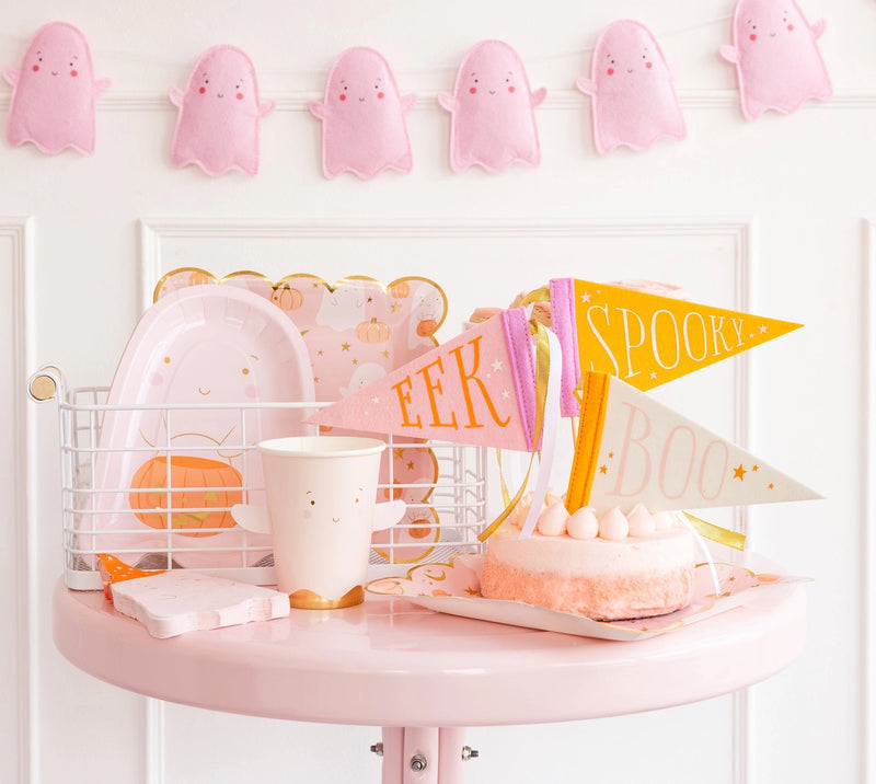 A pink Halloween party setup featuring ghost-themed party decorations, including ghost-shaped napkins, pink ghost cups, and mini pennant flags. Perfect for adding a playful touch to your Halloween party decorations.