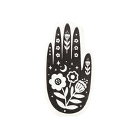 Close-up of a black and white hand-shaped Halloween paper napkin with floral and moon designs, perfect for spooky party decor.