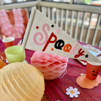 A colorful Halloween party table setup featuring a felt 'Spooky' Halloween flag alongside decorative paper lanterns and a perfect addition to your boo basket.