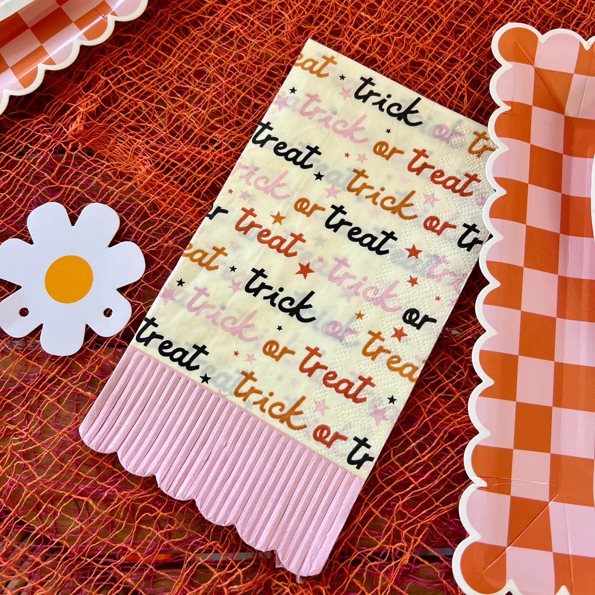 Close-up of 'Trick or Treat' Halloween napkins with pink fringe, adding a playful and spooky touch to the Halloween party table setup.