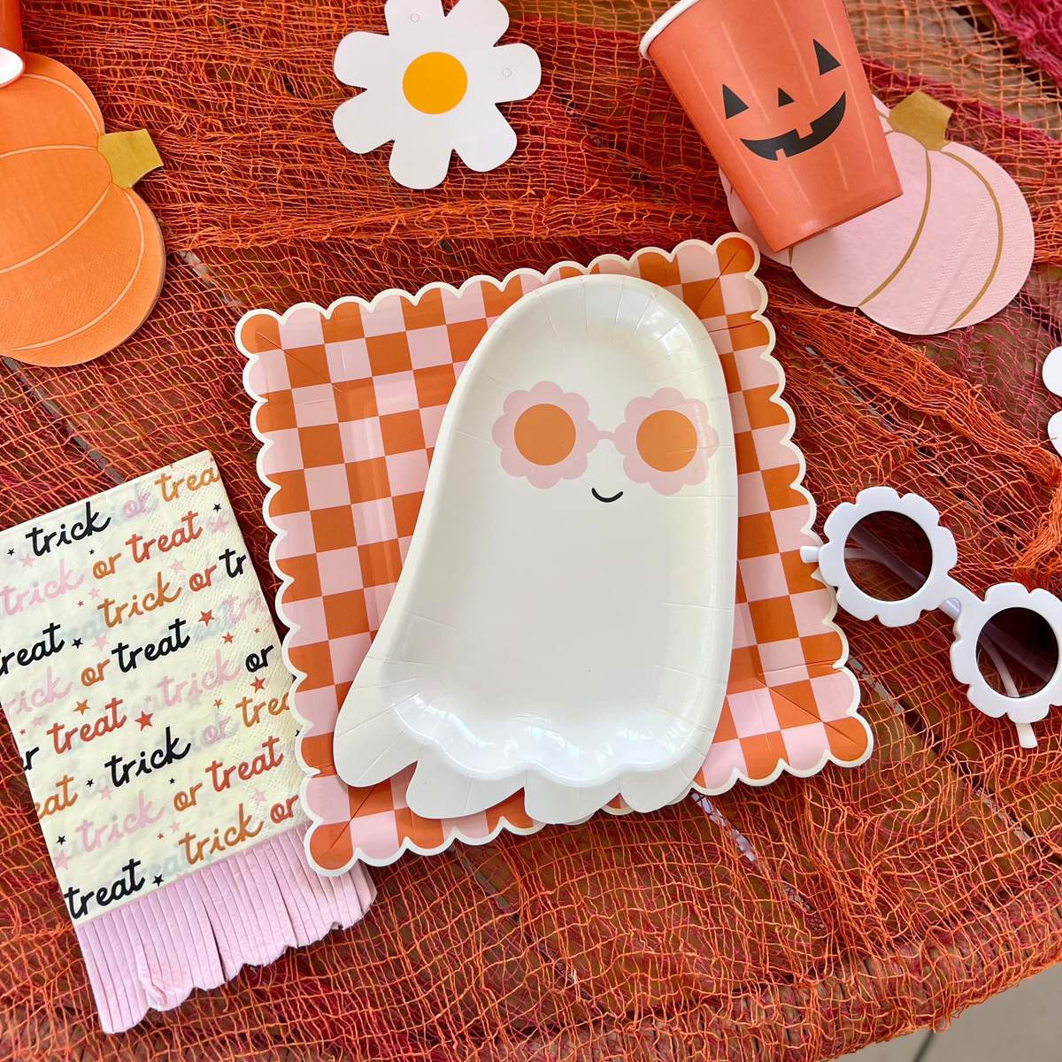 A colorful Halloween-themed table with orange and pink decorations, including 'Trick or Treat' Halloween napkins and matching plates, perfect for a Halloween celebration.