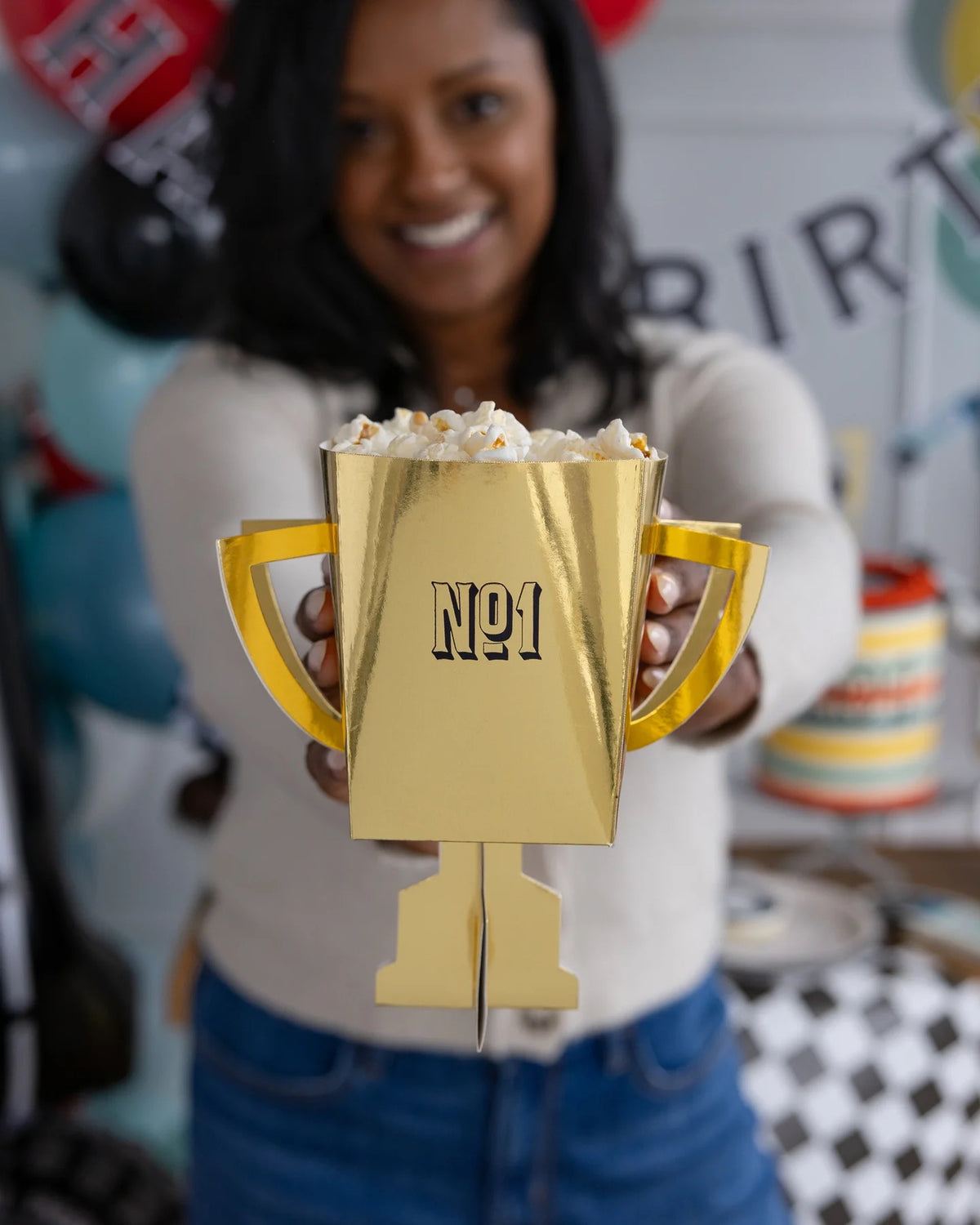 Children holding Miles Per Hour Trophy Treat Cups filled with goodies at a Two Fast Birthday party.