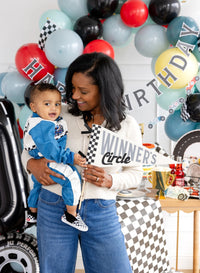 Miles Per Hour Winners Circle Felt Pennant hanging above the cake table at a Two Fast Birthday car-themed party.