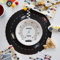 Styled speedometer plates on a race track table setup with colorful car-themed birthday party decor and snacks.