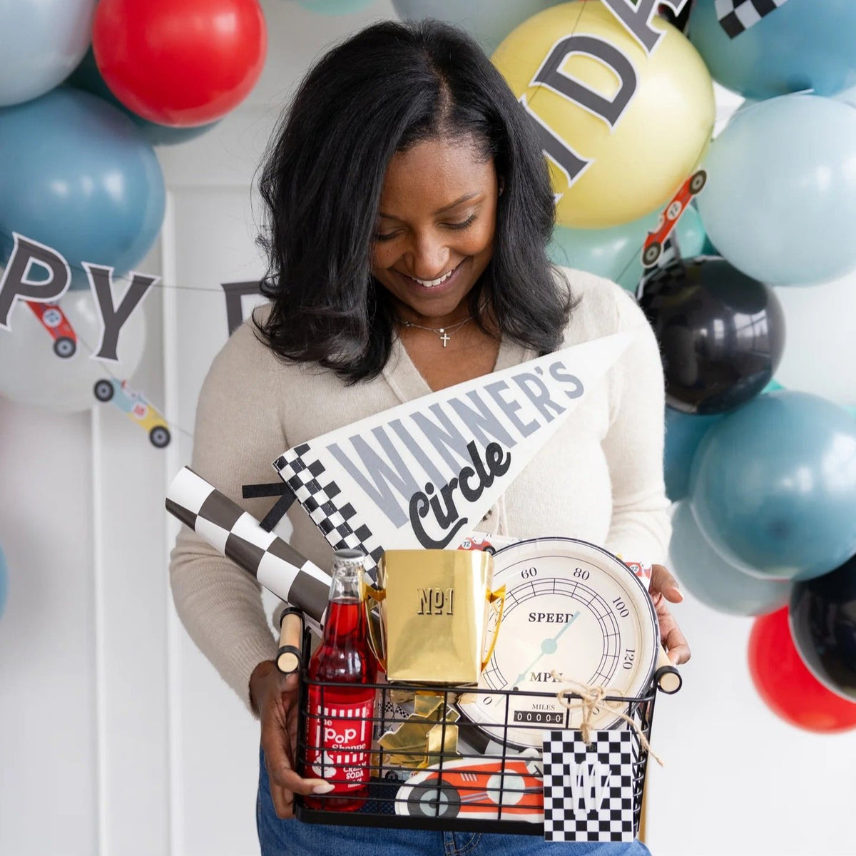 Guest holding a Winner’s Circle basket with speedometer plates and car-themed birthday party decor for a race day-inspired celebration.