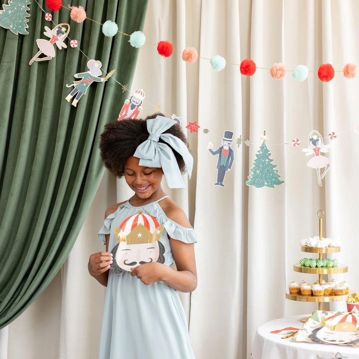 little girl in front of the The Nutcracker Party Banner holding a nutcracker plate