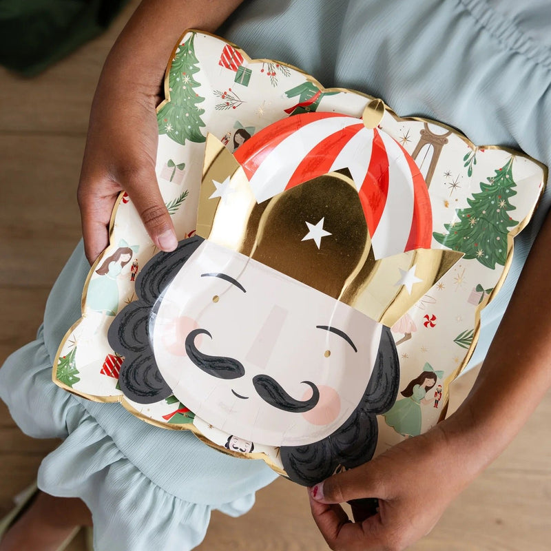 Little girl holding a set of Christmas paper plates with nutcracker designs