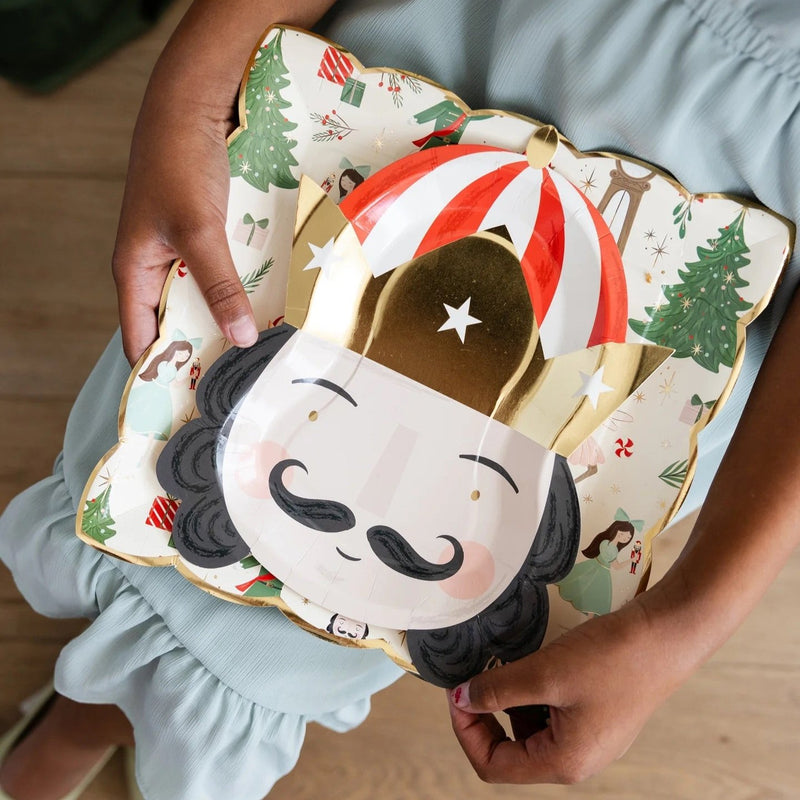 Little girl holding a set of Christmas paper plates with nutcracker designs