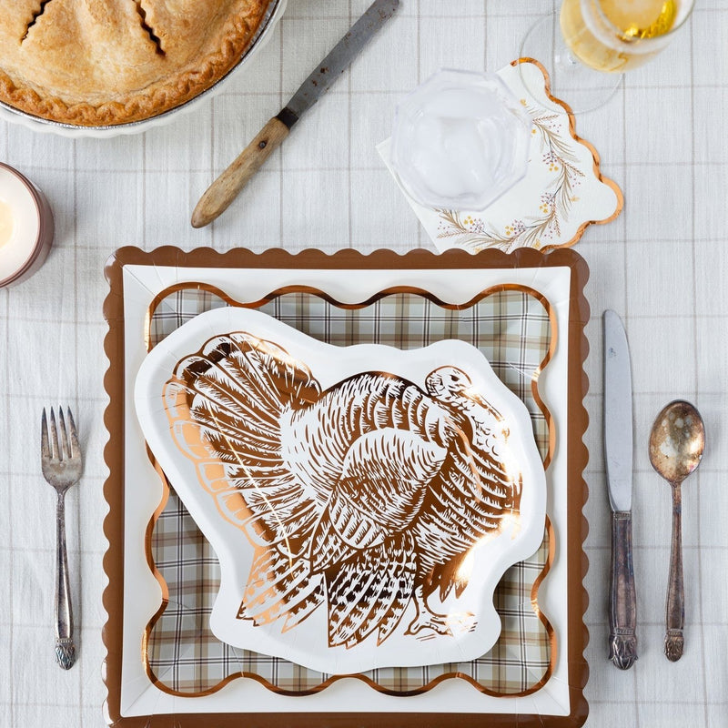 Stylish Thanksgiving table setting featuring a golden turkey plate and plaid square plates, making a chic statement for your Thanksgiving party decor.