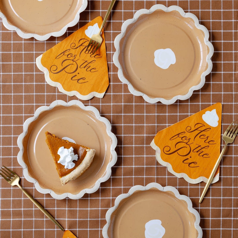 A fun and festive Thanksgiving table setup featuring "Here for the Pie" Thanksgiving napkins shaped like pie slices, paired with scalloped-edge plates and gold utensils. This playful Thanksgiving table decor brings a charming touch to your holiday celebration.