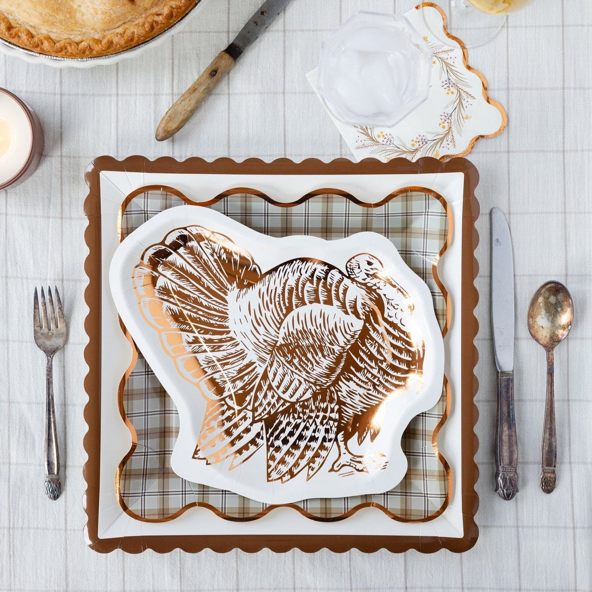 A beautifully set Thanksgiving table featuring plaid Thanksgiving paper plates and a turkey-shaped plate. This fall table decor creates a warm and inviting atmosphere, perfect for a festive harvest meal.