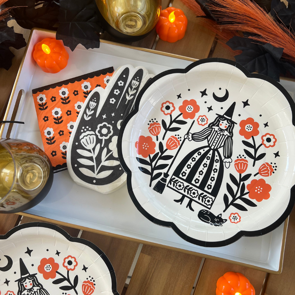 Halloween party setup with witch plates, hand-shaped napkins, and floral orange napkins from the Halloween party kit. Ideal for a party in a box.