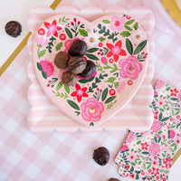 Floral scalloped paper dinner napkins styled on a festive table with baby shower or Valentine’s party decor.