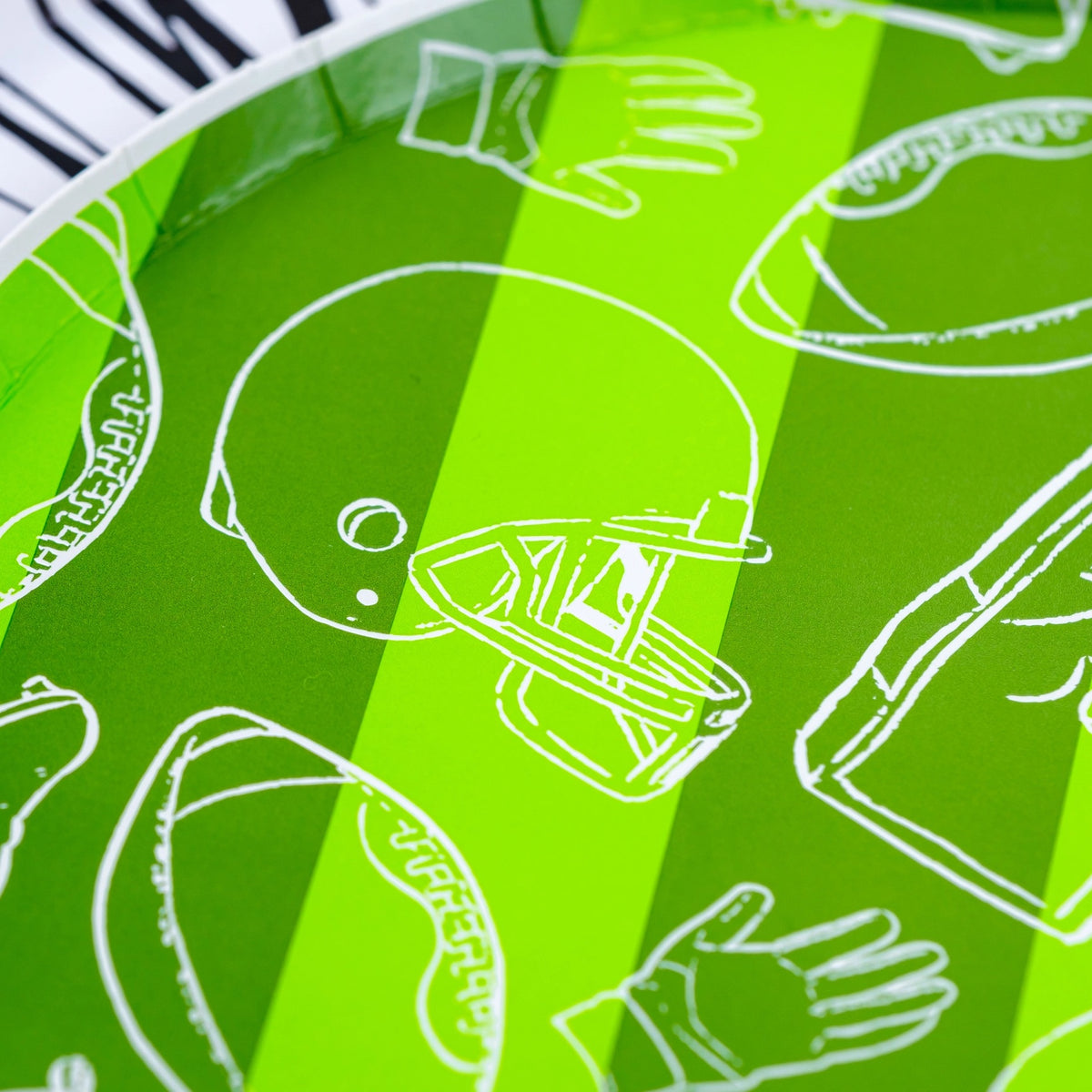 Detailed view of a green striped football paper plate with white football-themed icons, perfect for football-themed party supplies and tailgate decorations.