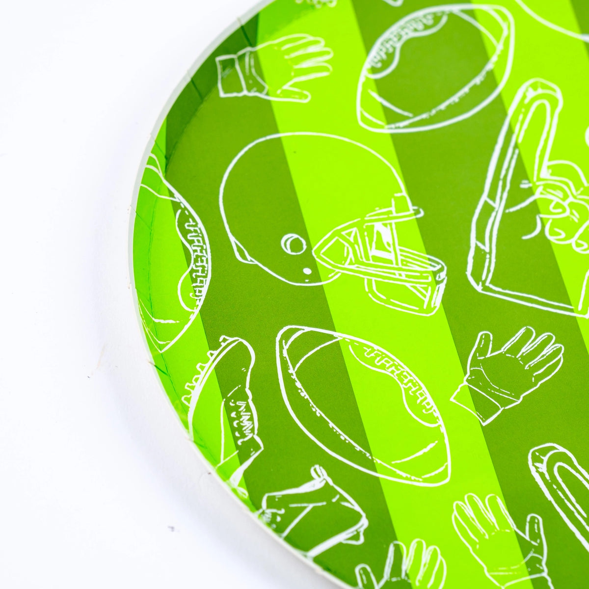 Side angle of a green striped football paper plate featuring a football-themed motif, great for game day tableware and tailgate party setups.