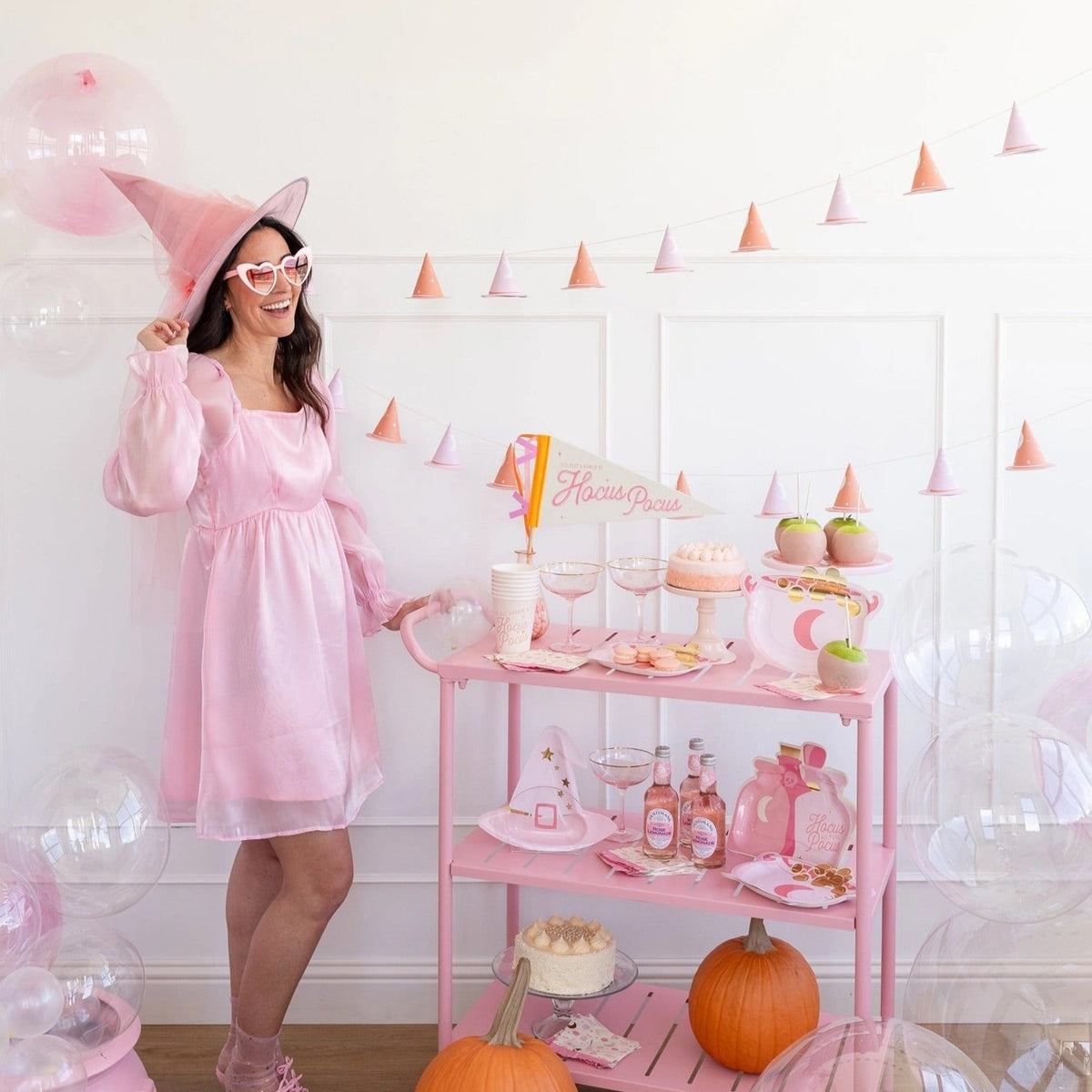 6-foot Halloween garland with 12 pink and gold witch hats, featuring glittery brims and gold foil stars, hung against a white wall.