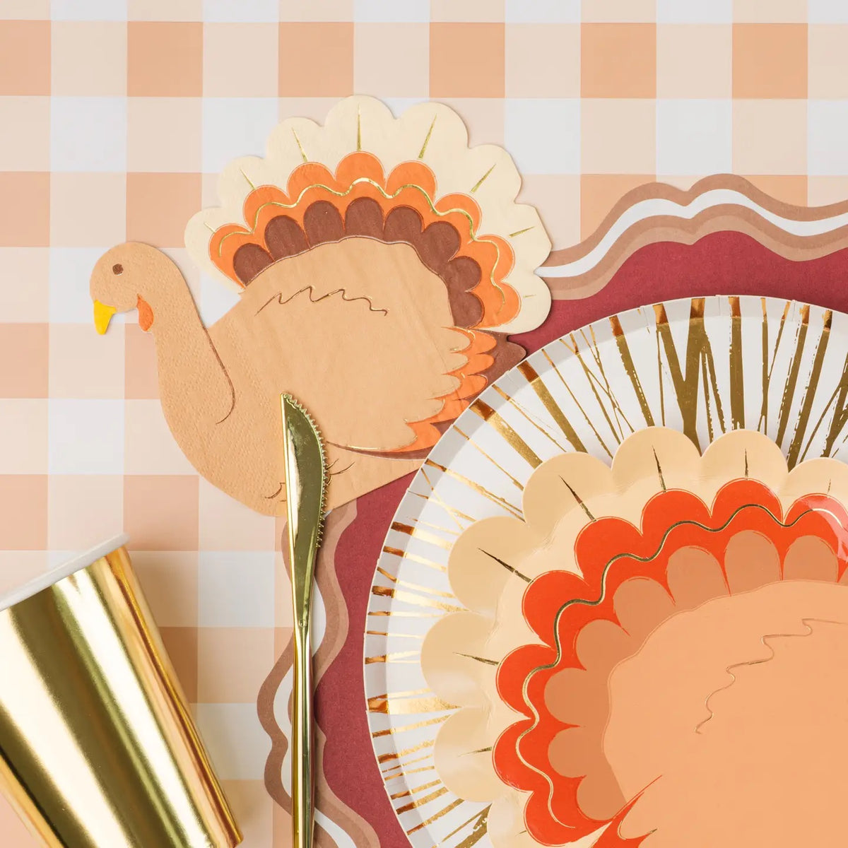 A Thanksgiving tablescape with turkey napkins arranged beside a plate, gold cutlery, and a gold cup, completing a warm and festive holiday setting. Perfect Thanksgiving paper napkins for any fall gathering.