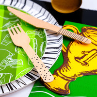 Football paper plate set against a striped table runner and golden trophy napkin, perfect for football-themed party supplies and tailgate party decorations.