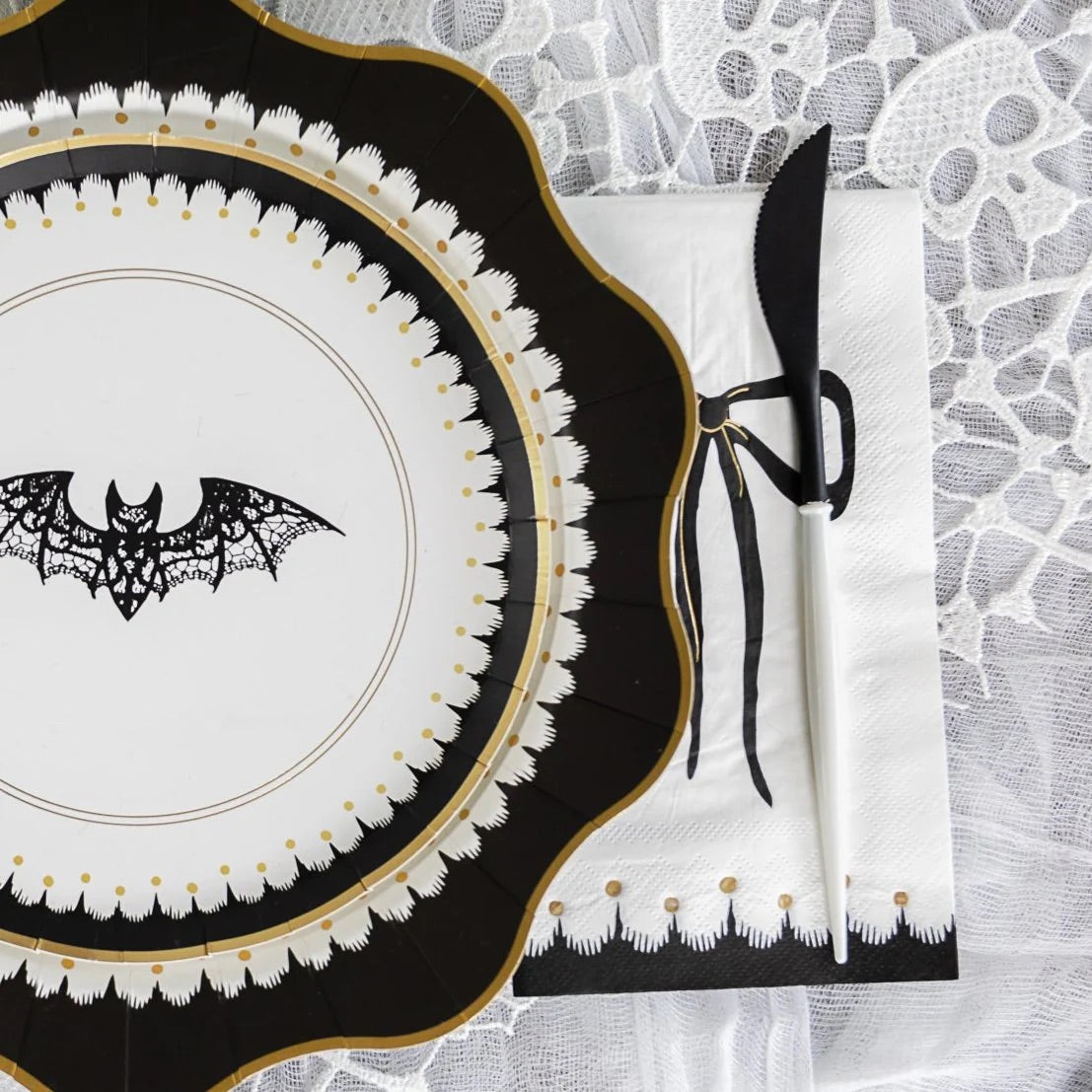 A close-up shot of an elegant Halloween plate with a bat design, paired with a black-bowed Halloween paper napkin. Classy Halloween decorations bring a refined edge to this spooky place setting.