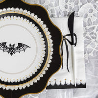 A close-up shot of an elegant Halloween plate with a bat design, paired with a black-bowed Halloween paper napkin. Classy Halloween decorations bring a refined edge to this spooky place setting.