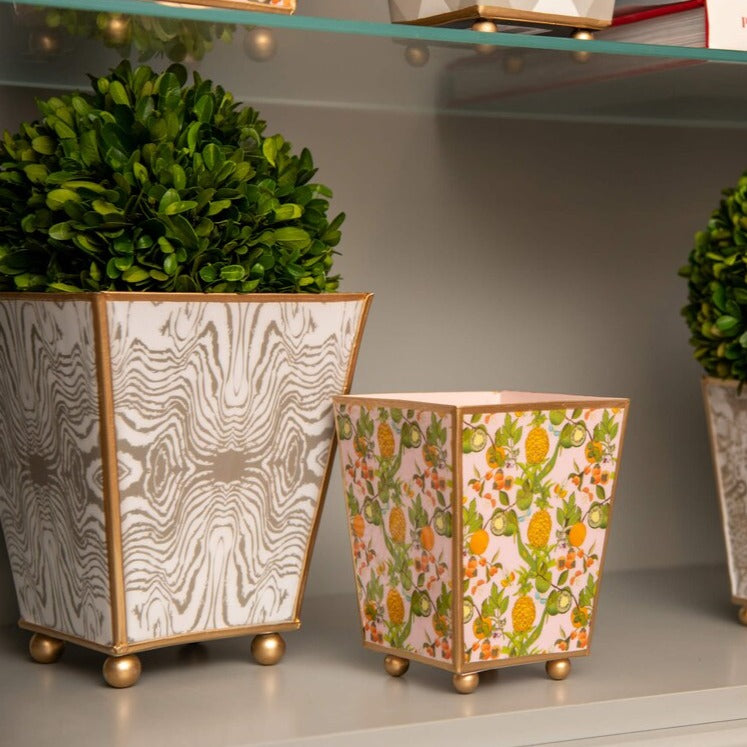 Make a statement with our Enameled Square Cachepot Planter, a playful yet practical table centerpiece. Decked out in a vibrant palette and a fruity motif of pineapples, limes, and oranges, this cachepot is trimmed in gold for that extra sparkle. Whether you're looking to brighten up your office desk, kitchen counter, or dining table, it offers a splash of spring and summer all year round. Versatile and visually stunning, it’s the centerpiece that brings your tablescape ideas to life.