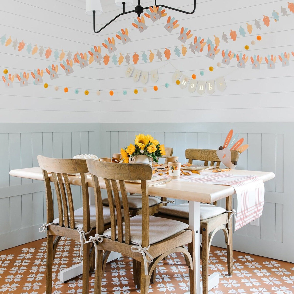 A cozy dining nook decorated with turkey garlands and Thanksgiving decor, ready to host a kids Thanksgiving table filled with playful, festive touches including fun cups and napkins.