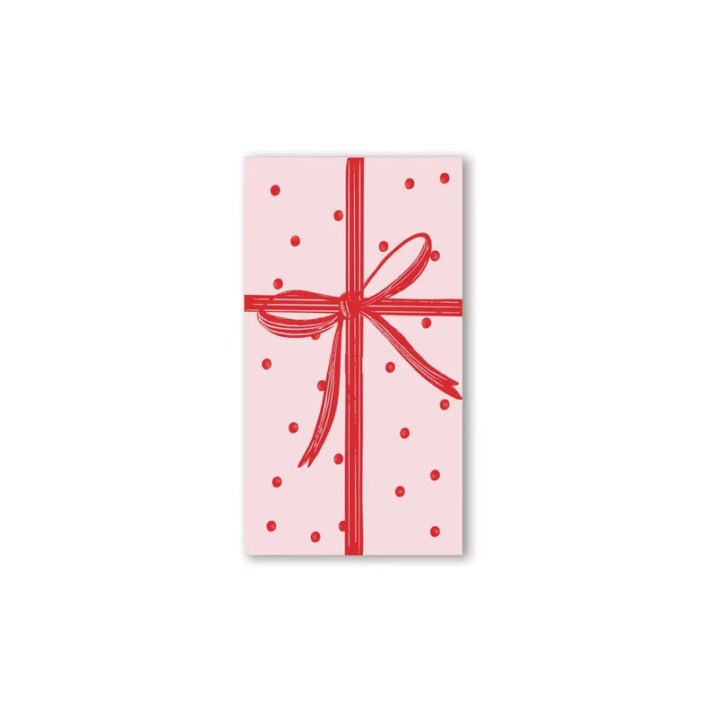 Paper Christmas napkins shaped like a pink wrapped gift with a red bow.